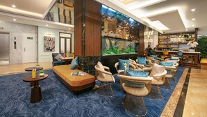A modern lobby with a bar area, seating with cushions, and a large aquarium. - Gloud Hotel (Hanoi)