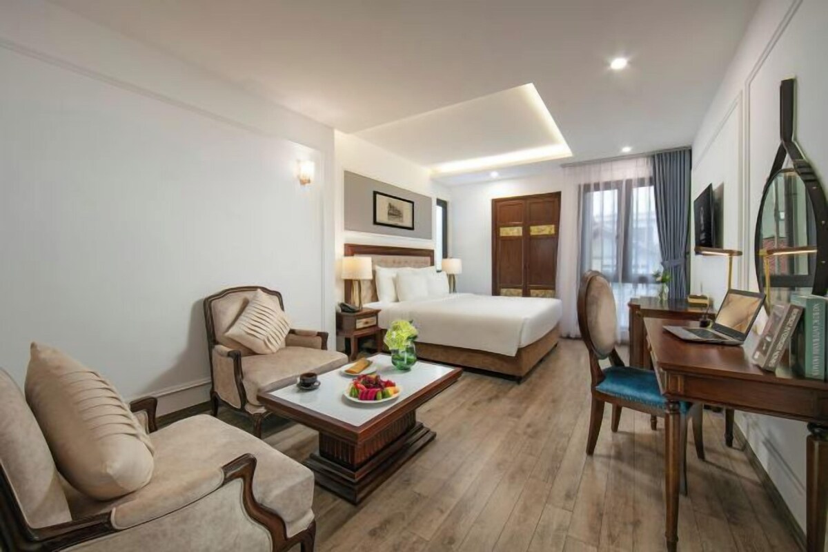 A hotel room with a bed, a sofa, a desk, and a coffee table.
