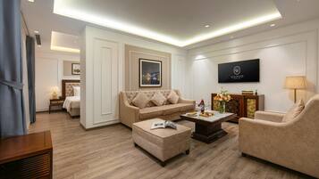 A modern living room with a beige sofa, a matching ottoman, a coffee table, and a TV mounted on the wall.