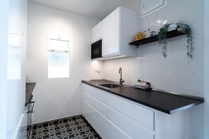 A modern kitchen with a black countertop, stainless steel sink, and white cabinetry.