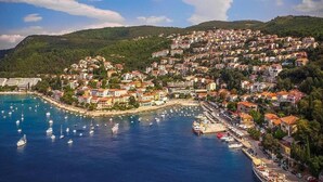 A coastal town with buildings on a hillside overlooking a marina with boats.