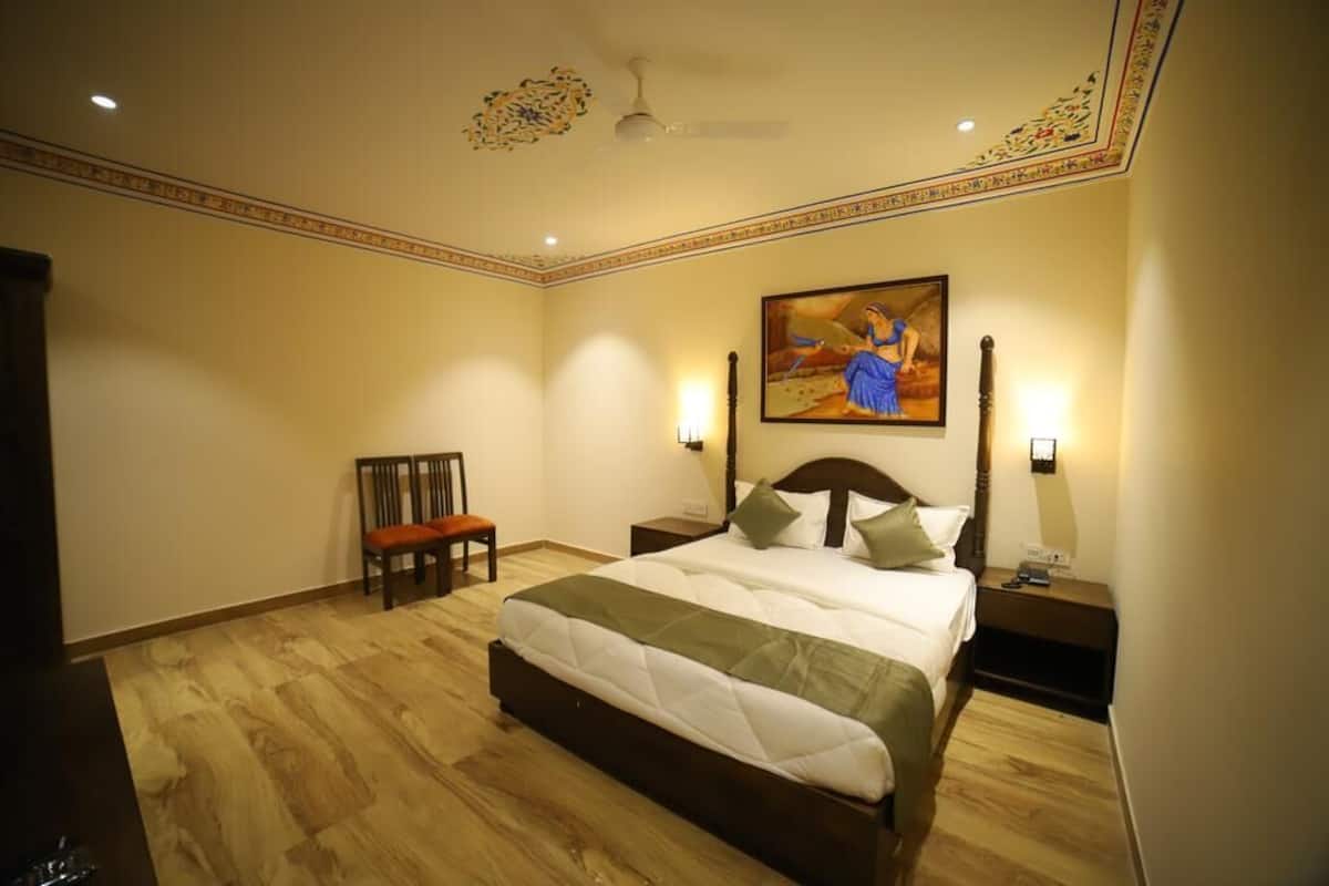 Un dormitorio con una cama grande, una silla, una mesita de noche y un cuadro en la pared.
