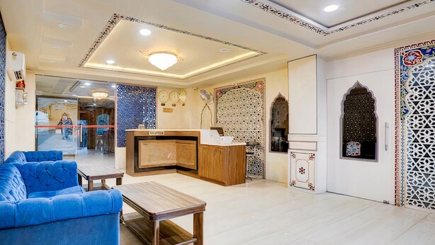 Un hall d’hôtel comprenant un comptoir d’accueil, un espace salon et des panneaux muraux décoratifs.