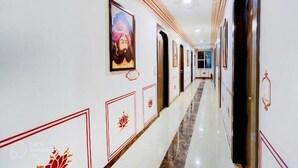 Un couloir aux murs ornés de tableaux encadrés, avec des portes et un sol en marbre poli.