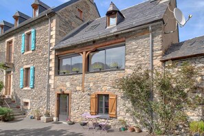 A stone building with multiple windows, a door, and a satellite dish.