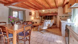Un interior de madera con una mesa de comedor, sillas, un sofá, chimenea y una zona de cocina.
