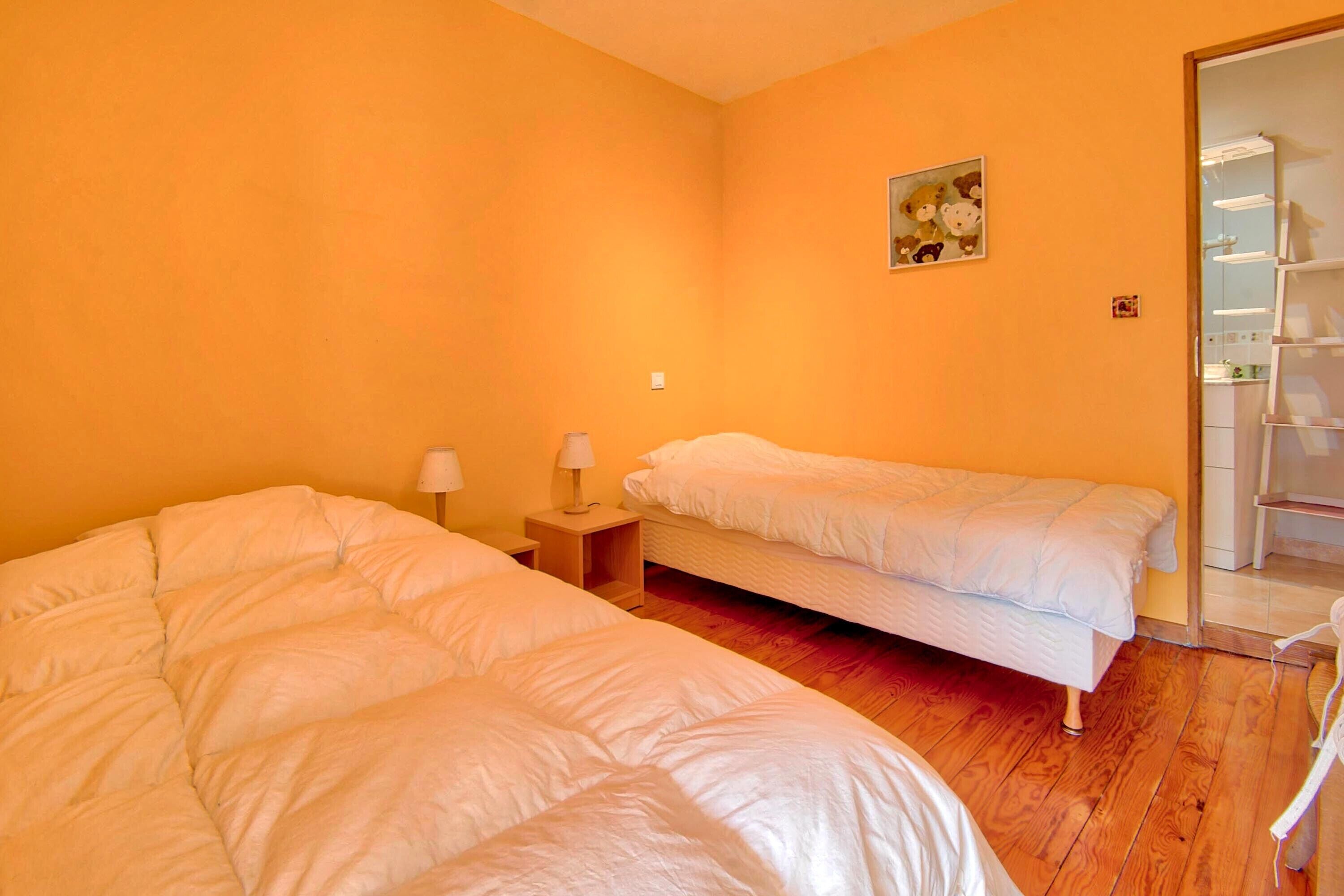 Une chambre avec deux lits, un plancher en bois, une petite table de chevet avec une lampe et un miroir.