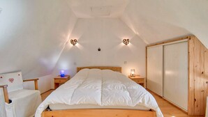 Un dormitorio con una cama de madera, lámparas de noche, una silla y un armario.