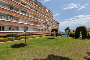 Ein mehrstöckiges Hotel mit Balkonen, einem Swimmingpool und gepflegten Rasenflächen.