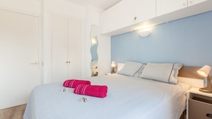 Une chambre à coucher avec un lit, des oreillers, une table de chevet, une lampe et une armoire.