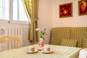 Ein Essbereich mit einem für Tee gedecktem Tisch, einer Blumenvase und einem mit Vorhängen versehenen Fenster.