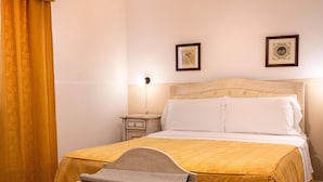 Habitación de hotel con cama, mesita de noche, lámpara y dos cuadros en la pared.