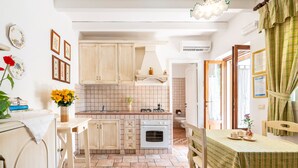 Una cocina con armarios de madera, salpicadero de azulejos, una estufa y un comedor con una mesa preparada para dos.