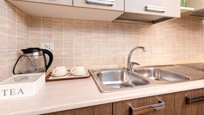 A kitchen with a double sink, a coffee maker, and a tea set on the counter.