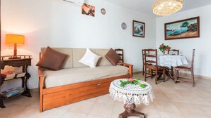 A living room with a sofa, a table with a lace tablecloth, a chandelier, and a painting on the wall. - Apartment 'Férias Lagos' with Balcony, Wi-Fi and Air Conditioning (Lagos)
