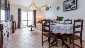 A dining area with a table set for four, a chandelier, and a painting on the wall. - Apartment 'Férias Lagos' with Balcony, Wi-Fi and Air Conditioning (Lagos)