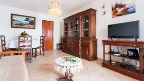 A living room with a dining area, a wooden cabinet, a television, and a chandelier. - Apartment 'Férias Lagos' with Balcony, Wi-Fi and Air Conditioning (Lagos)