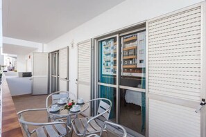 Une chambre d’hôtel avec un balcon, une table ronde avec des chaises et une porte-fenêtre coulissante donnant sur un espace piscine.