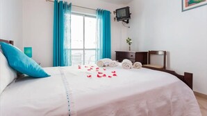 A bedroom with a bed, a TV, a dresser, and a window with curtains. - Apartment 'Férias Lagos' with Balcony, Wi-Fi and Air Conditioning (Lagos)
