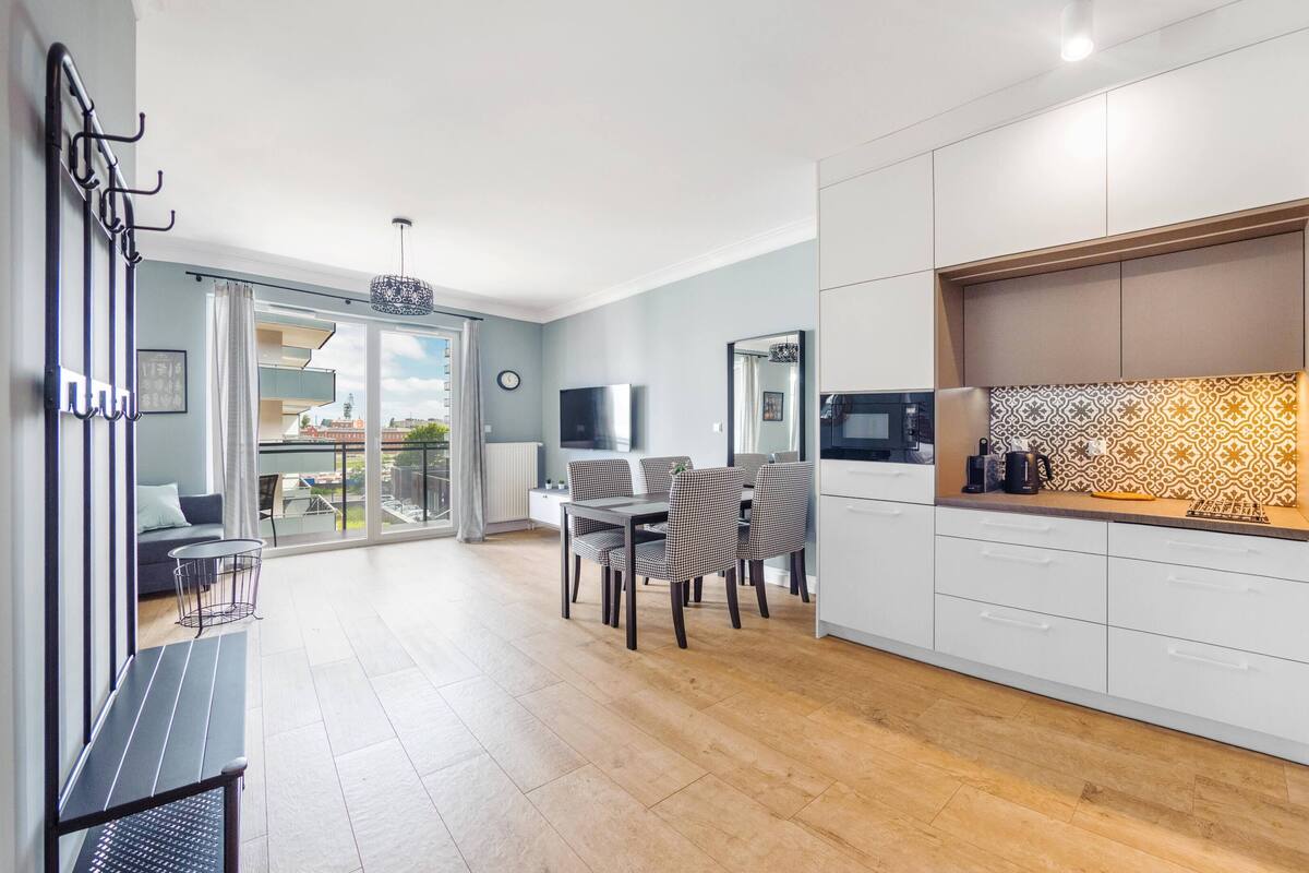 Un apartamento moderno con comedor, cocina y un balcón con vistas a la ciudad.