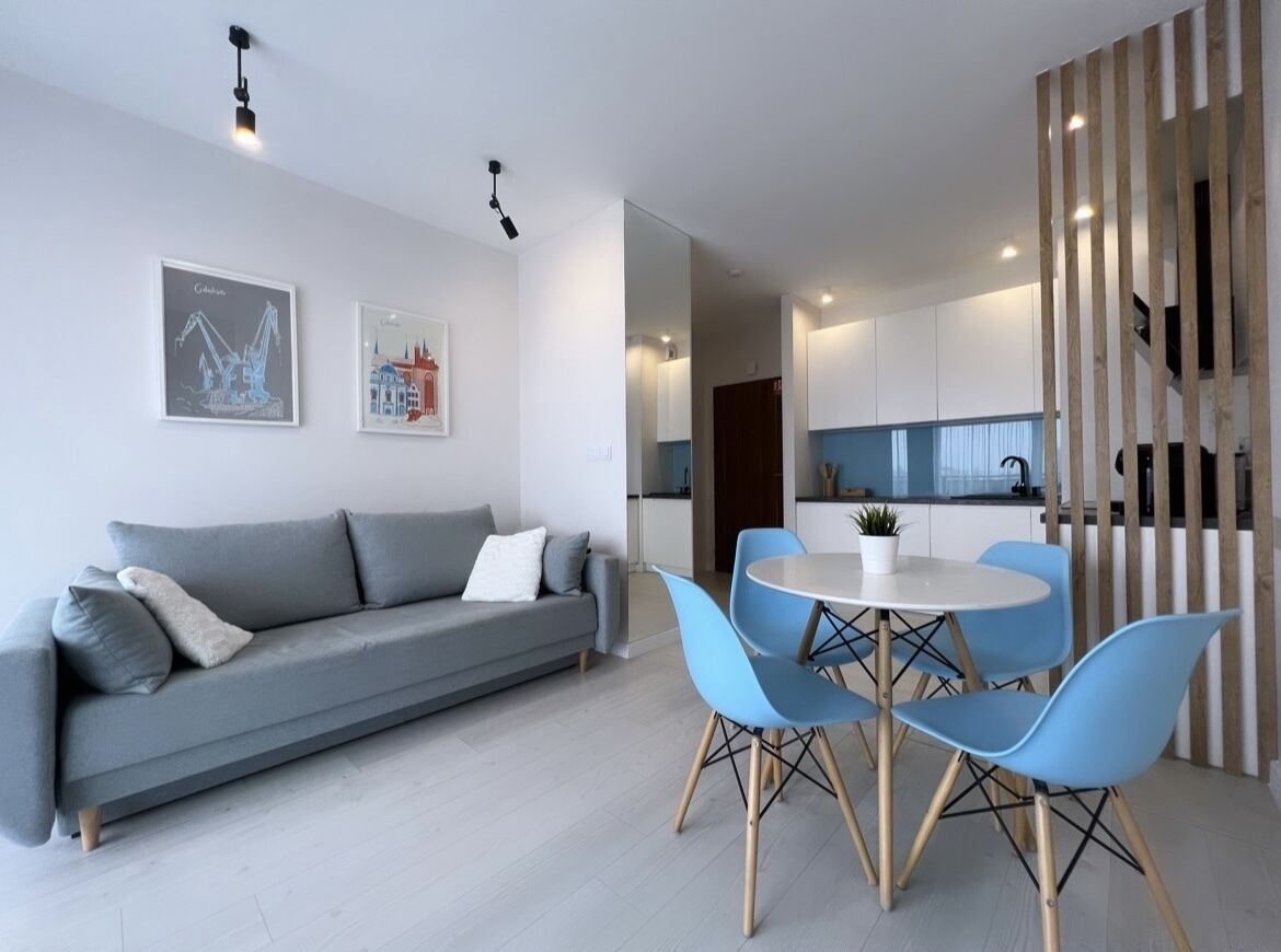 Un salon moderne avec un canapé gris, des fauteuils bleus et une table à manger.