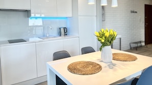 A modern kitchen with white cabinets, a stainless steel kettle, and a blue-lit backsplash. - Bastion Wałowa by Q4Apartments (Gdansk)