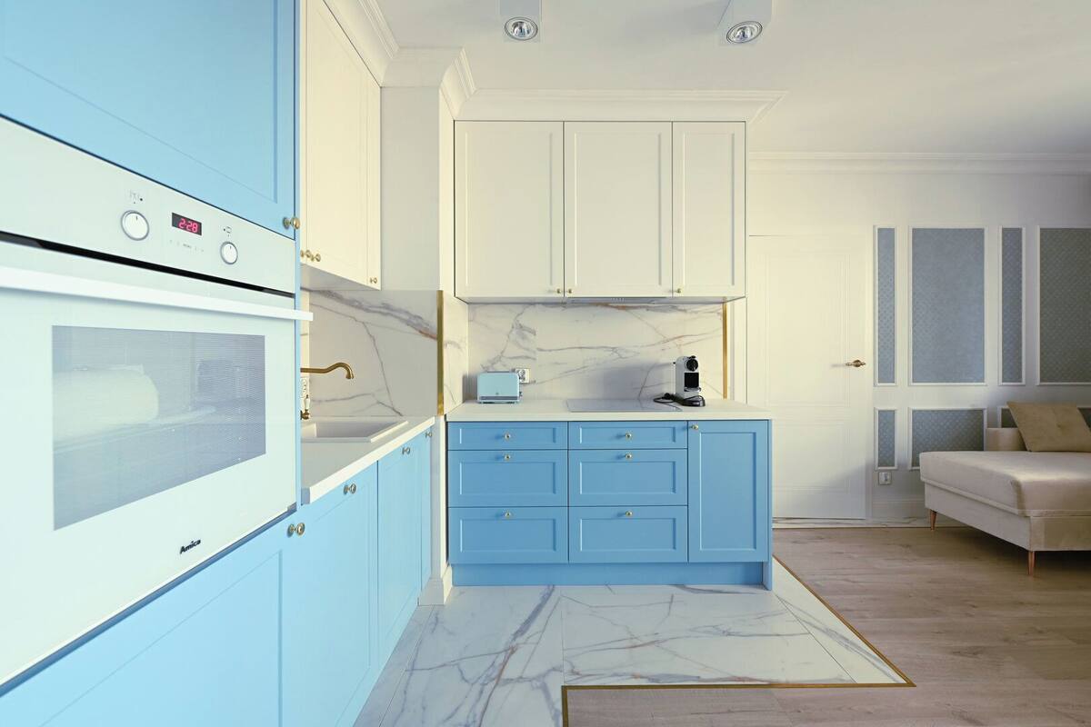 Una cocina moderna con armarios azules, una encimera blanca y un salpicadero de mármol.