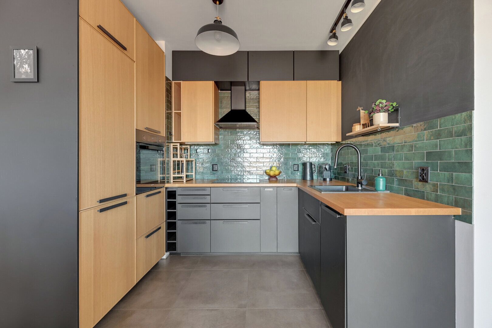 Une cuisine moderne avec des meubles en bois, un plan de travail gris et un pare-feu en carreaux.