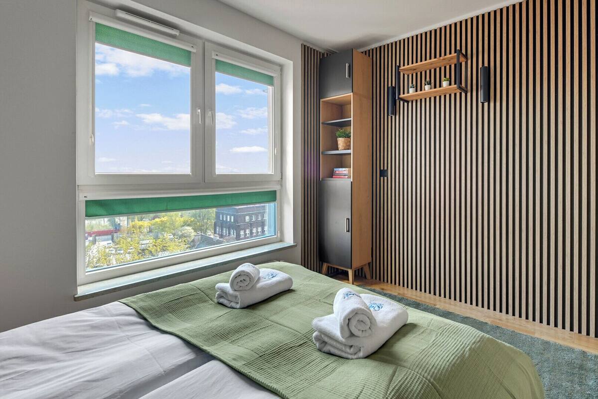 Una habitación de hotel con cama, ventana con vistas, armario y estante con objetos.
