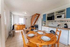 Une cuisine compacte avec un coin repas, des meubles en bois et un lave-linge.