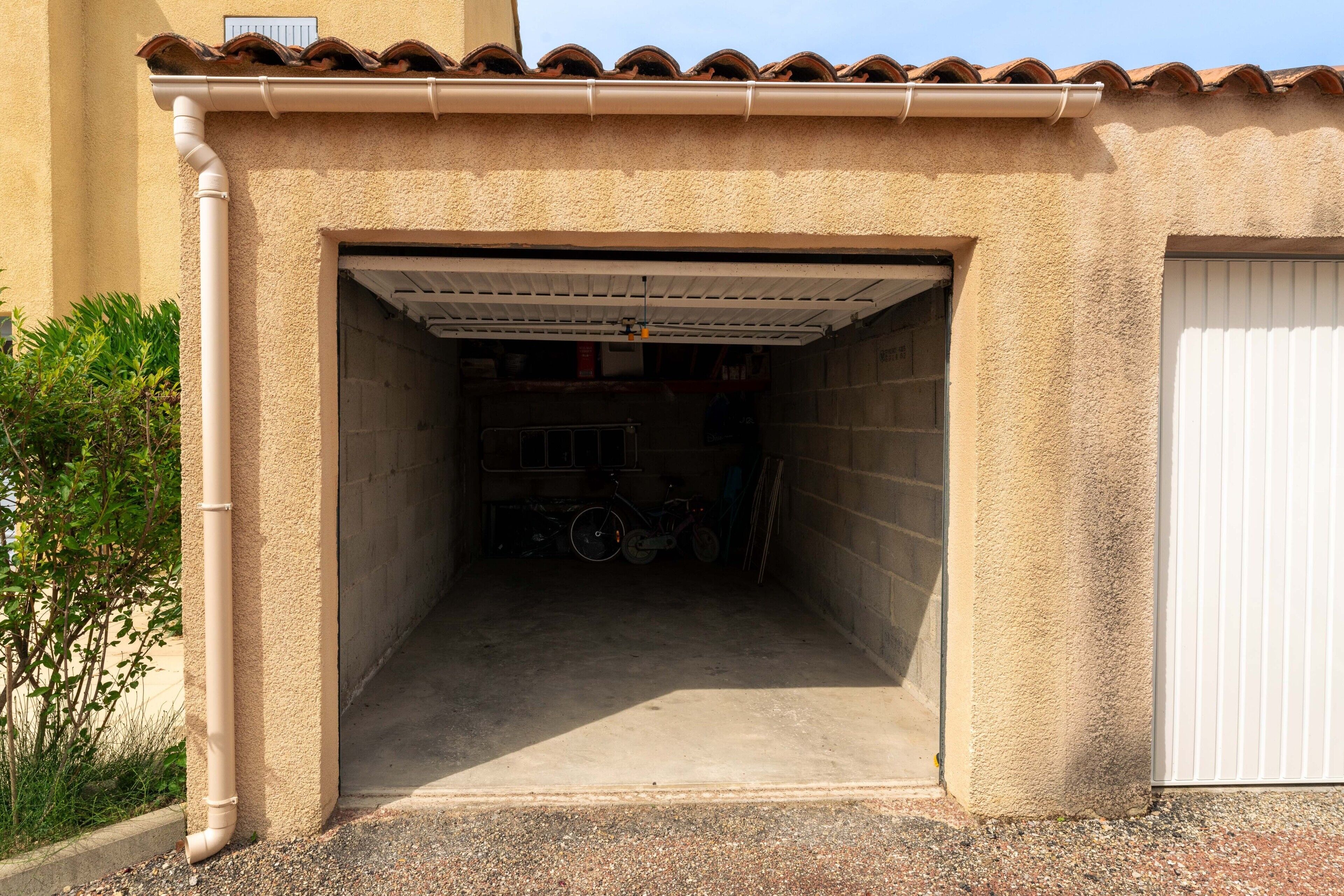 Un garage avec un sol en béton, un vélo et une porte de garage fermée.