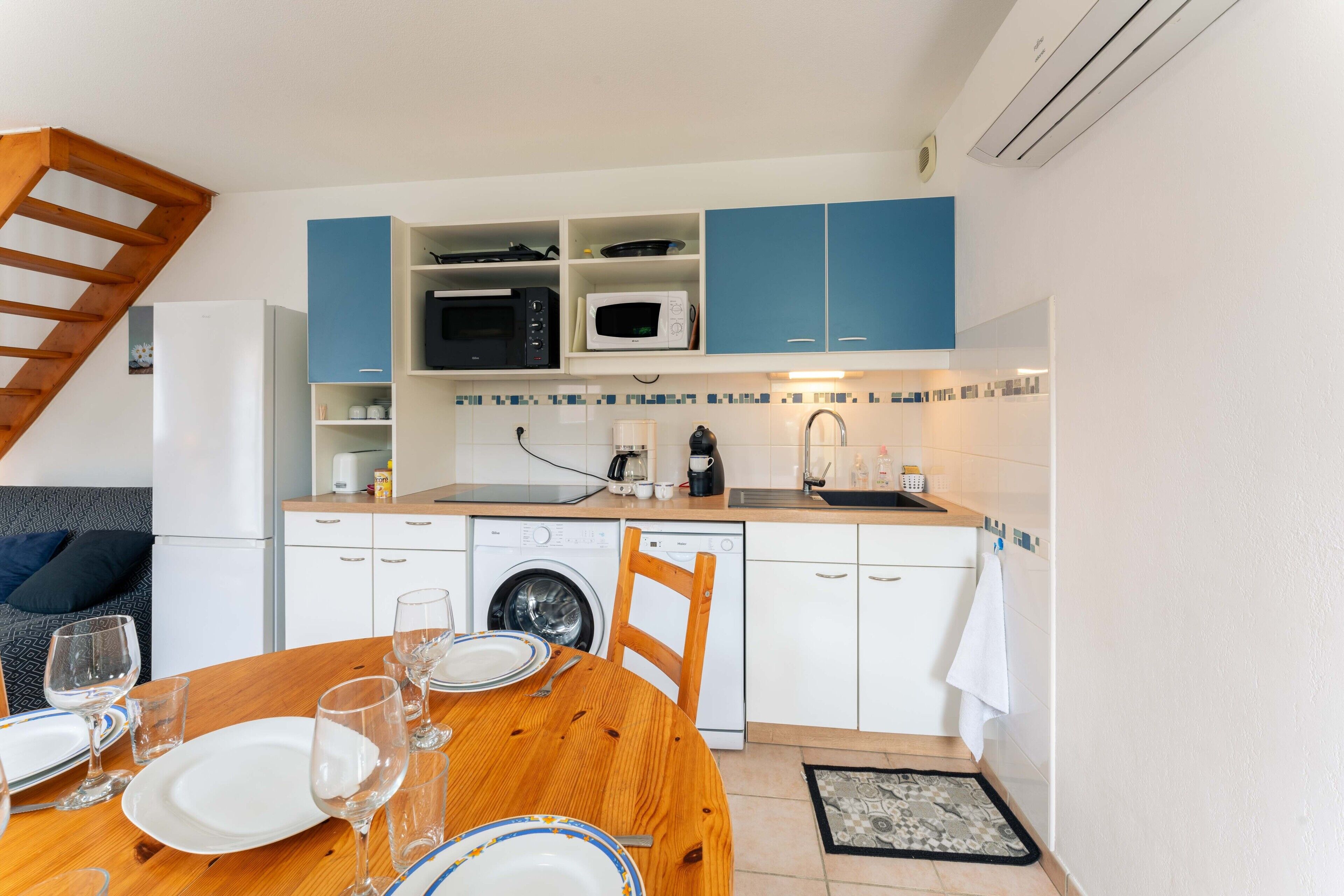 A compact kitchen with a dining table set, a washing machine, and a microwave.