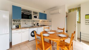 Cozinha compacta com mesa de jantar, cadeiras, máquina de lavar e micro-ondas.