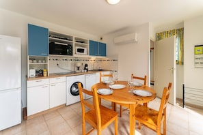 Une cuisine compacte comprenant une table à manger, des chaises, un lave-linge et un four à micro-ondes.