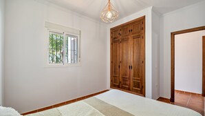 Un dormitorio con una cama grande, un armario de madera, una ventana y una lámpara colgante.