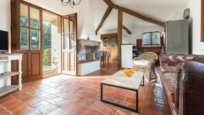 A spacious living area with a fireplace, a leather sofa, and a dining table. - Villa 'Casa Di Pruno' with Private Pool, Wi-Fi and Air Conditioning (Figari)