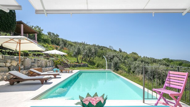 A pool with lounge chairs and a pink chair, surrounded by greenery and a clear sky. - Holiday Home 'Casetta Maya' with Sea View, Wi-Fi and Air Conditioning (Riparbella)