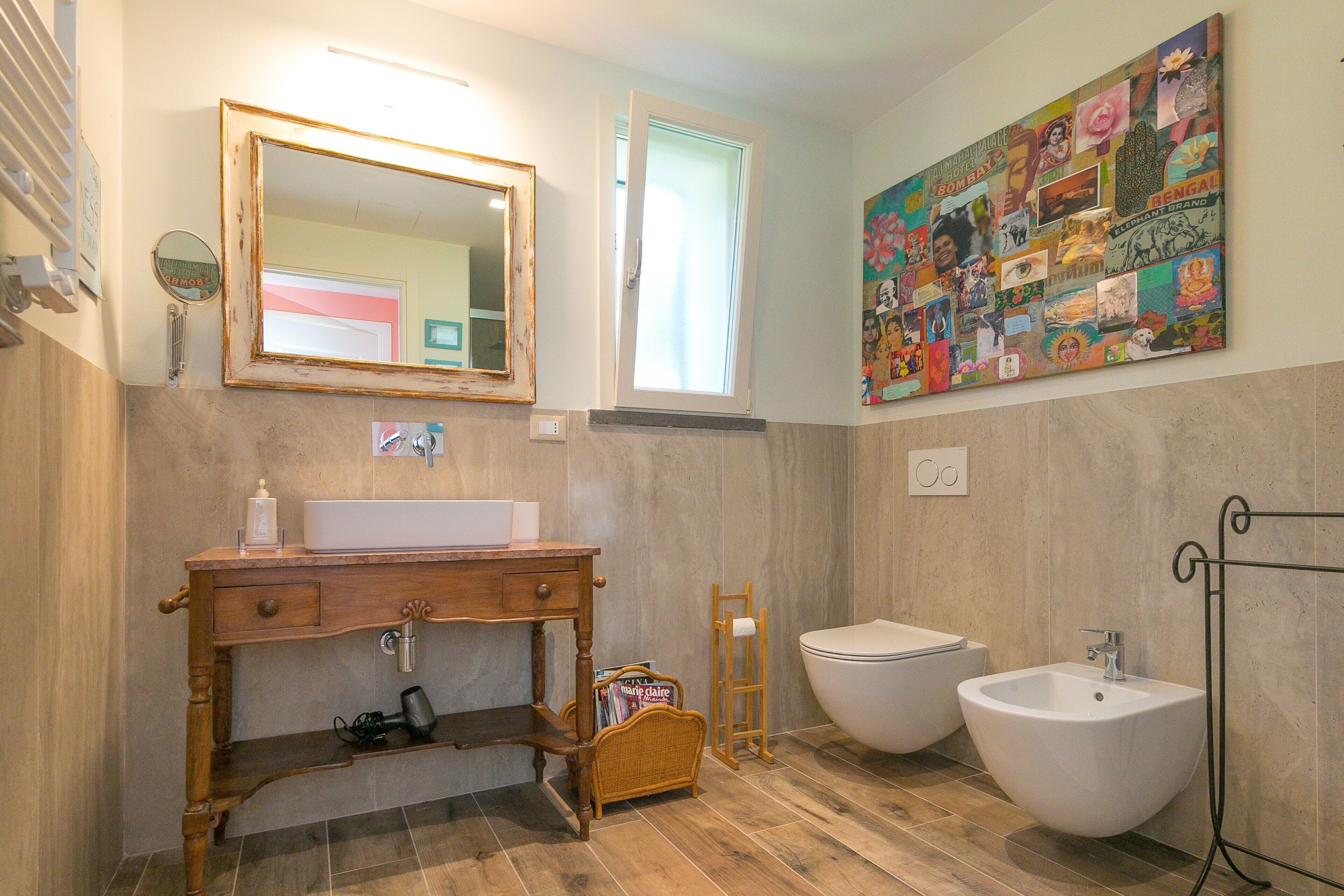 Un bagno con mobiletto in legno, due lavabi, uno specchio e un'opera d'arte a parete.