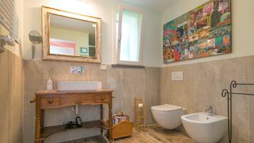 Un bagno con mobiletto in legno, due lavabi, uno specchio e un'opera d'arte a parete.
