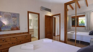 Un dormitorio con una cama grande, un aparador de madera, un espejo y zona de ducha.