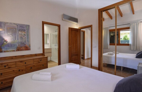 Ein Schlafzimmer mit einem großen Bett, einem Holzschrank, einem Spiegel und einer Duschkabine.