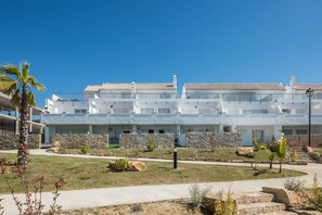 Un hôtel moderne à plusieurs étages, doté de murs en pierre et d’une pelouse bien entretenue.