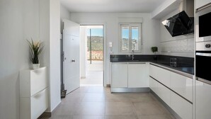 A modern kitchen with white cabinetry, a black countertop, and a built-in oven. - Apartment 'Apartamento Poniente' with Sea View, Wi-Fi and Air Conditioning (Zahara de los Atunes)