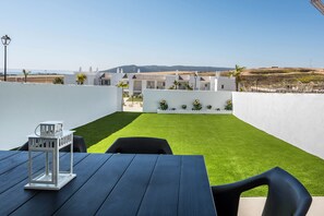 Une terrasse avec une table et des chaises, une lanterne blanche et une vue sur des bâtiments et des collines.