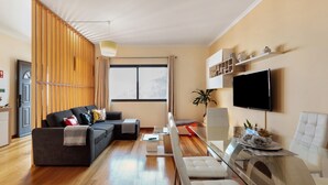 Un salon moderne comprenant un canapé, une table basse, un téléviseur et un coin repas avec des chaises.