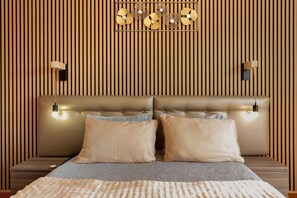 Une chambre à coucher avec une tête de lit capitonnée, deux lampes de chevet et un panneau décoratif mural.