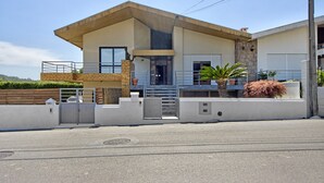 A modern two-story house with a gated entrance, a balcony, and a small garden area.