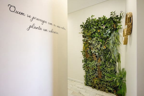 A wall with a vertical garden and a decorative wooden piece.