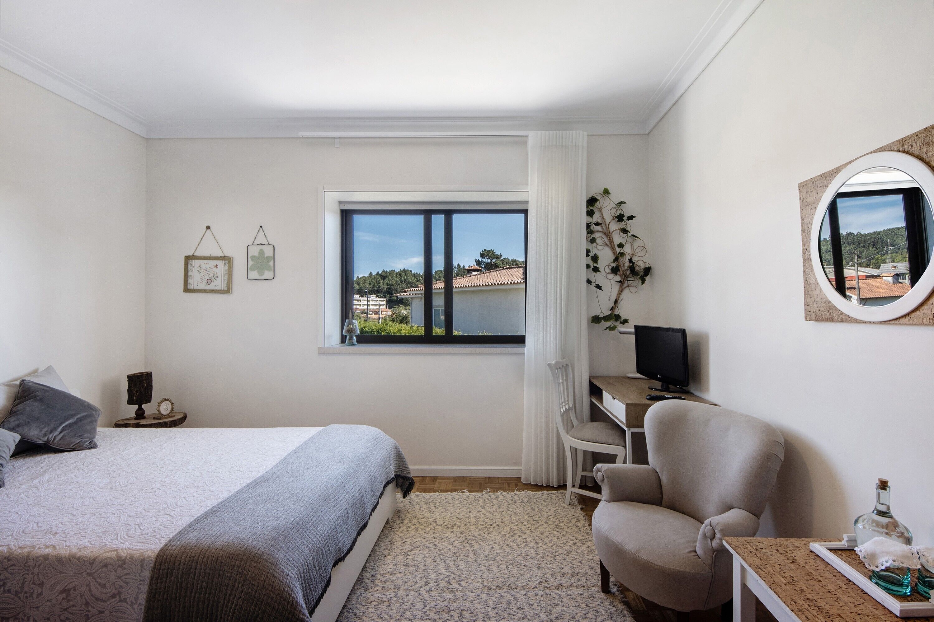 Ein Schlafzimmer mit Bett, Schreibtisch, Stuhl und Fenster mit Blick nach außen.