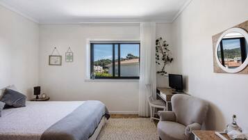 Ein Schlafzimmer mit Bett, Schreibtisch, Stuhl und Fenster mit Blick nach außen.
